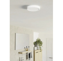 Plafonieră LED rotundă și plată într-o baie luminoasă, cu un design modern, oglindă, poliță și plantă.
