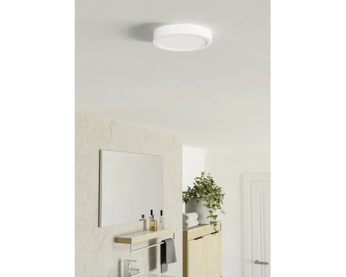 Plafonieră LED rotundă și plată într-o baie luminoasă, cu un design modern, oglindă, poliță și plantă.