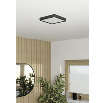 Plafonieră LED pătrată într-o cameră luminoasă, cu design modern, cu panouri de perete cu aspect de lemn, o oglindă ovală și o plantă de apartament.