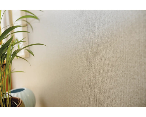 Tapet cu model fin tip os de pește și aspect textil pe un perete, lângă o plantă de apartament.
