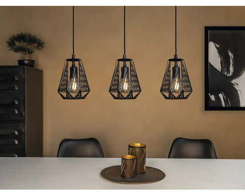 Pendul cu trei brațe cu abajururi din sârmă metalică neagră și becuri vizibile deasupra unei mese de dining într-un interior modern.
