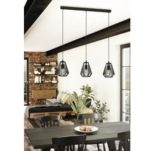 Lustră suspendată cu trei brațe, design industrial, cu abajururi din cușcă metalică neagră deasupra unei mese într-o cameră modernă.