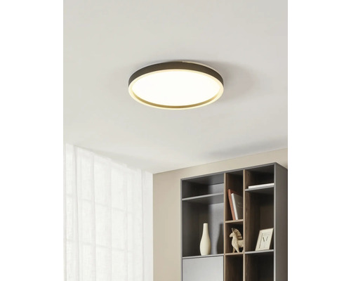Plafonieră LED modernă, rotundă, într-un interior minimalist, deasupra unui raft gri închis.