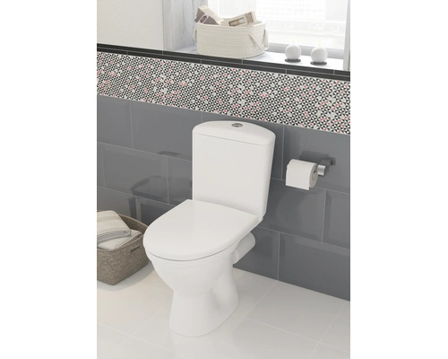 Baie modernă cu toaletă albă cu montaj pe pardoseală, pereți placați cu gresie gri și bordură decorativă cu model geometric.