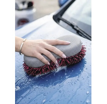 O mână spală capota unei mașini cu un burete de spălat auto din microfibră cu două fețe și apă cu săpun.