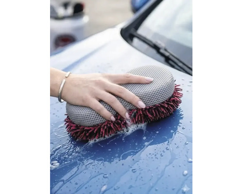 O mână spală capota unei mașini cu un burete de spălat auto din microfibră cu două fețe și apă cu săpun.