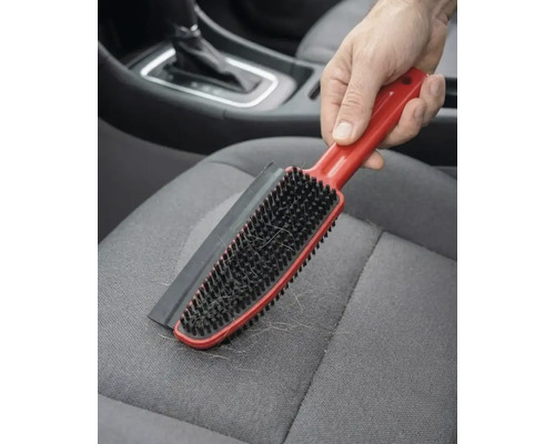 Perie pentru îndepărtarea părului de animale cu margine de cauciuc pe un scaun auto din material textil.