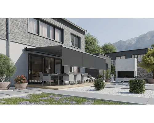 Marchiză de terasă modernă cu volan retractabil montată pe o casă cu fațadă din cărămidă și grădină cu set de mobilier.