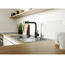 Chiuveta de bucatarie moderna din otel inoxidabil cu baterie monocomanda neagra pe un blat de lucru cu aspect de lemn intr-o bucatarie luminoasa.