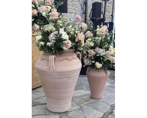 Două amfore mari din teracotă cu aranjamente florale pe o podea de piatră.
