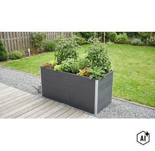 Jardinieră înaltă dreptunghiulară din plastic plantată cu roșii și ierburi aromatice pe o terasă din lemn în grădină. (Image AI modified or generated)