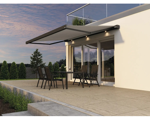 Marchiză de terasă modernă cu iluminare LED integrată deasupra unei terase cu set de mobilier exterior în fața unei case moderne.