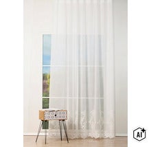 O perdea semitransparentă cu model brodat decorativ la bază, montată la fereastră într-o cameră luminoasă, amenajată modern. (Image AI modified or generated)