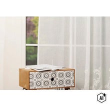 Perdea semitransparentă cu model ornamental în fața unei ferestre lângă o masă mică cu fațada sertarului cu model (Image AI modified or generated)