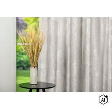 Perdea decorativă cu suprafață structurată în fața unei ferestre, lângă o vază cu grâu pe o masă rotundă de tip servantă. (Image AI modified or generated)