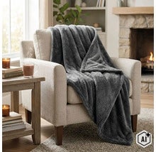O patura moale din fleece drapata peste un fotoliu intr-o sufragerie confortabila cu semineu. (Image AI modified or generated)