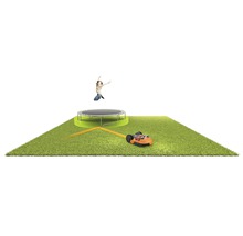 Suprafață cu gazon cu robot de tuns iarba, trambulină și copil sărind