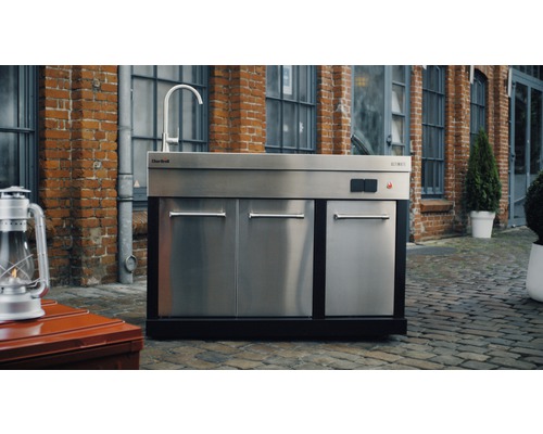 Bucătărie de exterior cu chiuvetă, dulapuri și robinet în fața unei clădiri din cărămidă