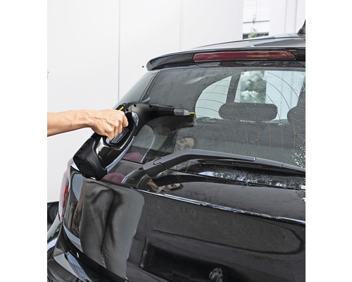 O persoană curăță luneta unei mașini cu un aspirator de geamuri.