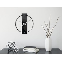 Ceas de perete cu indicatoare metalice și decorațiuni pe o comodă