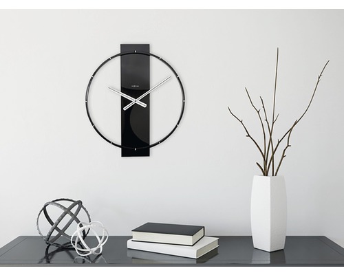 Ceas de perete cu indicatoare metalice și decorațiuni pe o comodă