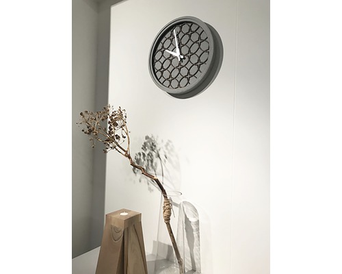 Ceas de perete cu model geometric deasupra elementelor decorative