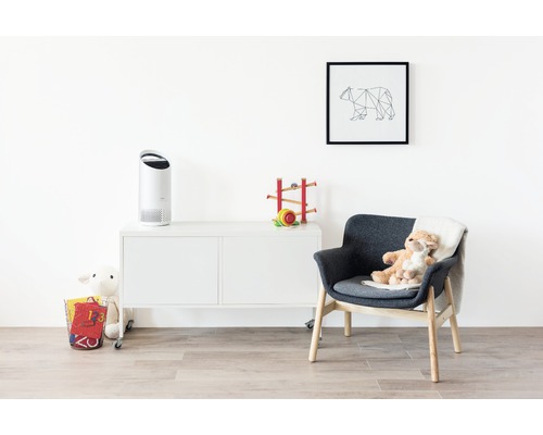 Cameră luminoasă cu purificator de aer pe o comodă, fotoliu cu jucării și o imagine cu un urs pe perete