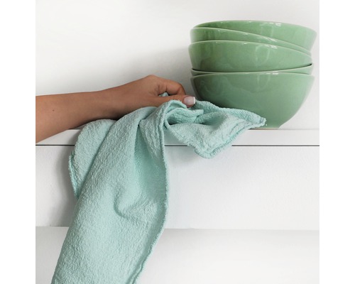 Femeie ștergând un teanc de boluri cu o cârpă