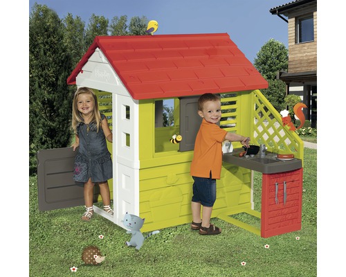 Căsuță de joacă din plastic cu bucătărie și doi copii care se joacă în grădină
