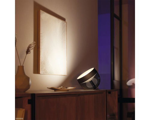 Interior cu o lampă de masă și o imagine iluminată pe perete