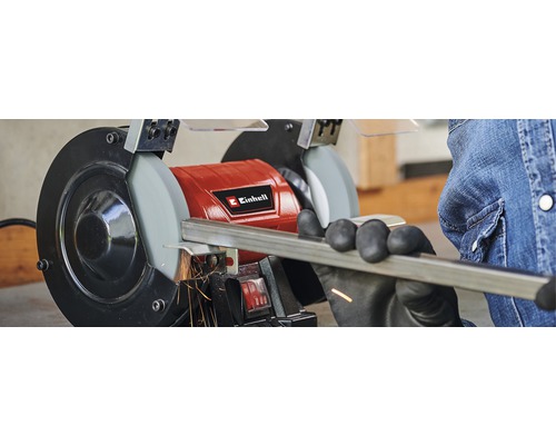 Un bărbat șlefuiește o bucată de metal cu o polizor de banc Einhell.