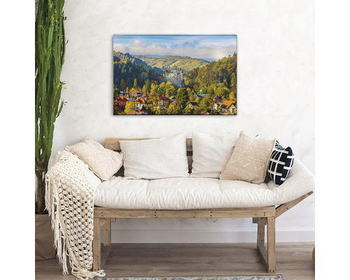 Decorarea camerei de zi cu o artă de perete care înfățișează un peisaj cu case și munți.