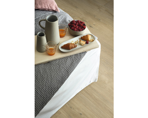 Tavă de mic dejun cu ulcior, pahare, zmeură și croissante pe un pat