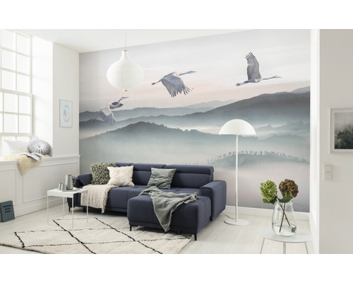 Living cu fototapet cu peisaj montan și cocori, canapea, covor și decorațiuni.