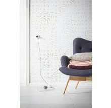 Scenă cu tapet cu model, fotoliu cu perne și decorațiuni și o lampă pe podea.