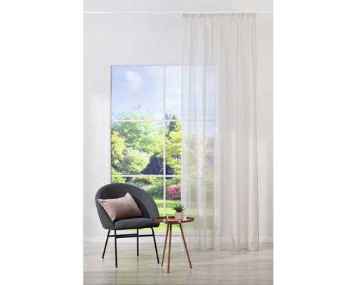 Living luminos cu draperie, scaun și măsuță laterală în fața unei ferestre cu vedere la grădină