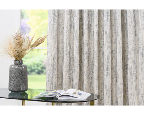 Perdea decorativă cu model lângă o masă cu vază și revistă