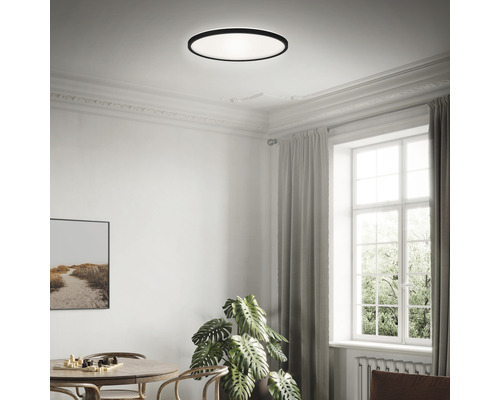 O cameră luminoasă cu o lampă de tavan rotundă, o masă și o fereastră.