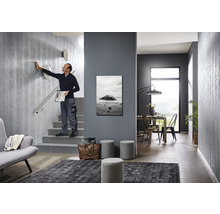 Scenă cu o scară cu design modern, cu o persoană care atinge un perete, mobilier și decorațiuni