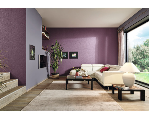 Cameră de zi cu canapea, masă, covor și plante de interior în fața unui perete cu model