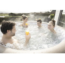 Familie cu băuturi se relaxează într-un jacuzzi gonflabil în aer liber.