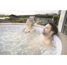 Un cuplu se relaxează într-un jacuzzi gonflabil în aer liber.