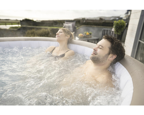 Un cuplu se relaxează într-un jacuzzi gonflabil în aer liber.