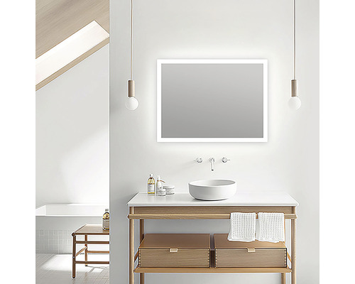 Baie modernă cu oglindă iluminată, lavoar și dulap de bază din lemn.