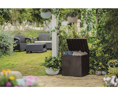 Scenă de grădină cu o cutie de depozitare din plastic deschisă și mobilier de grădină