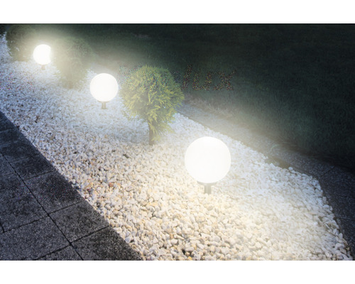 Scenă cu iluminat de grădină sferic de-a lungul unei căi acoperite cu pietriș