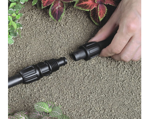 Două capete ale unui sistem de irigare sunt asamblate de o mână.