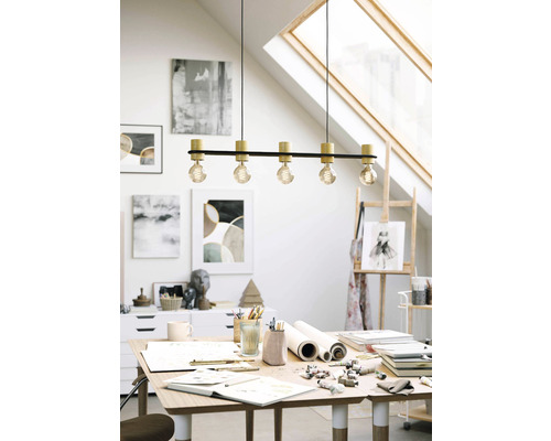 Scenă cu o lampă suspendată deasupra unei mese într-un atelier.