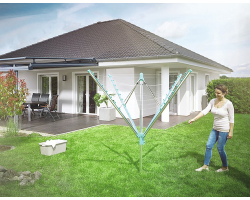 Uscător rotativ de rufe în grădină cu femeie, coș de rufe și casă individuală