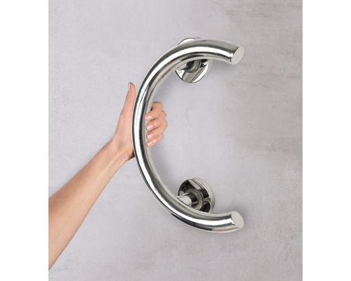 O persoană ține o bară de sprijin curbată din oțel inoxidabil pe perete.